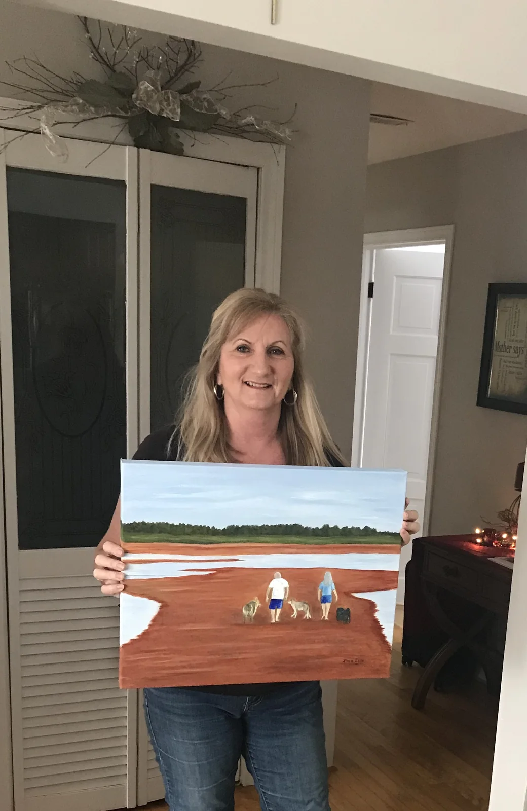 Wendy holding the finished painting of their dogs and beach walks